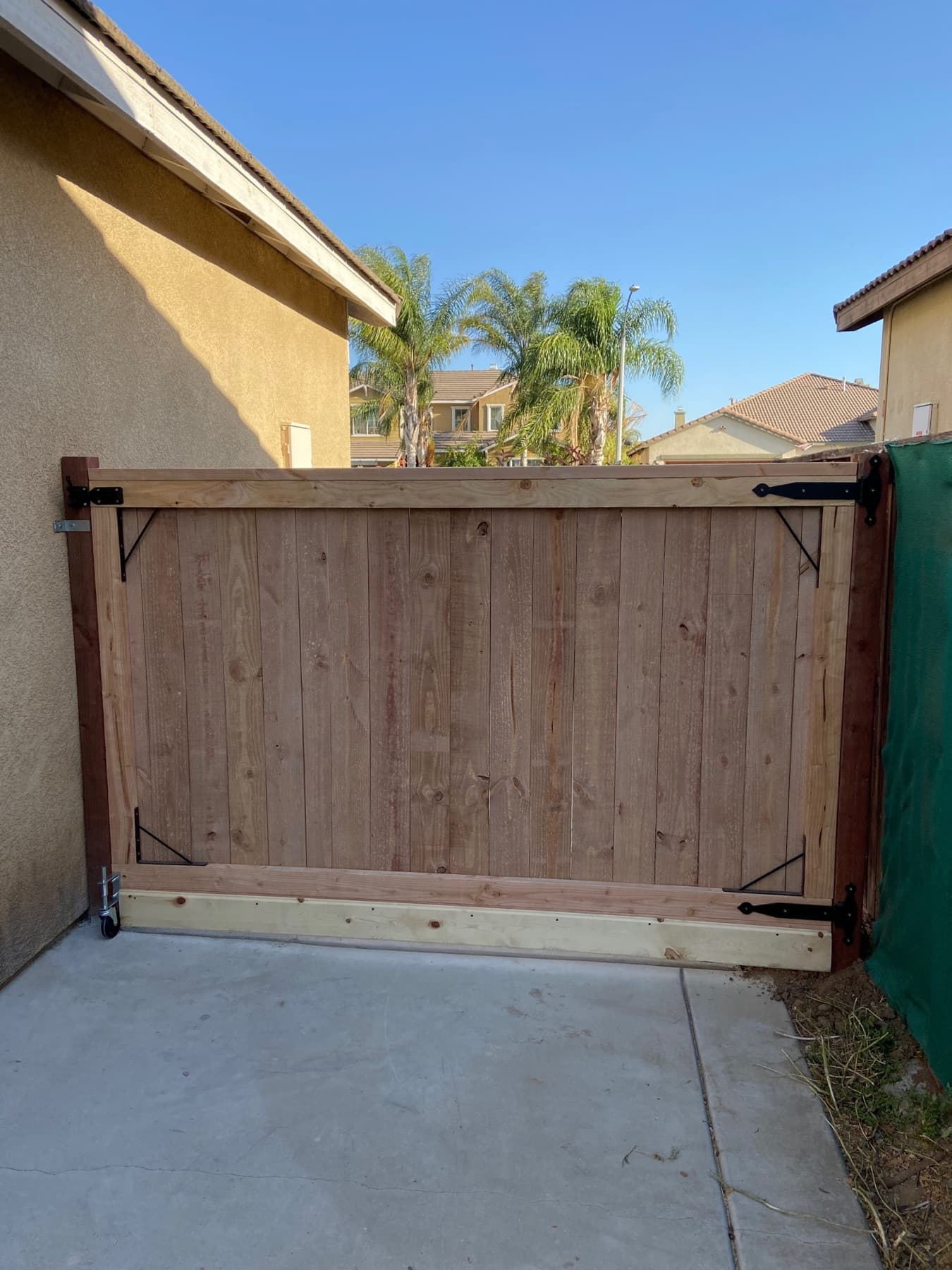 Braced wood RV gate on rollers beside a house